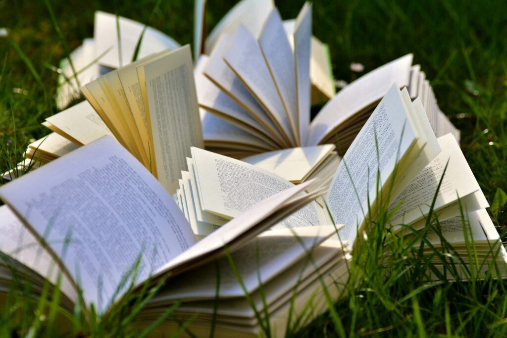 Several books open, scattered on grass.